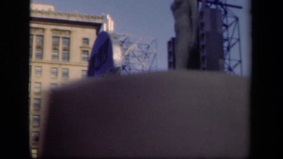 1941 New York home-movie frame showing a tall building, partial circular blue billboard, metal sign structure, and heavy dark frame edges.