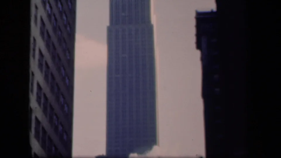 1941 New York frame with the Empire State Building tower centered between surrounding Manhattan high-rises.