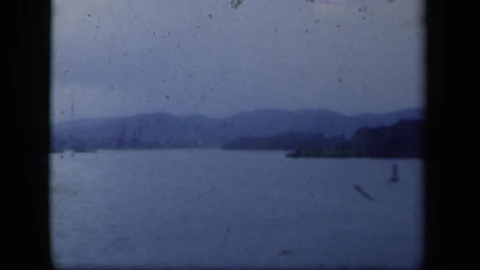 1941 New York lake landscape with blue-toned water, low mountain ridges, shoreline, and a small red buoy at right.
