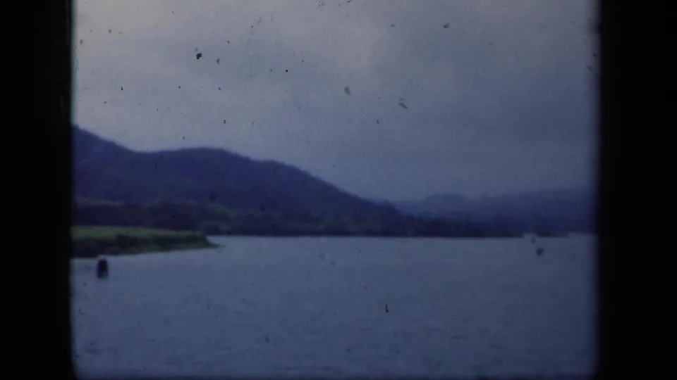 1941 New York 8mm view across open water toward a dark mountain ridge, with a small buoy visible.