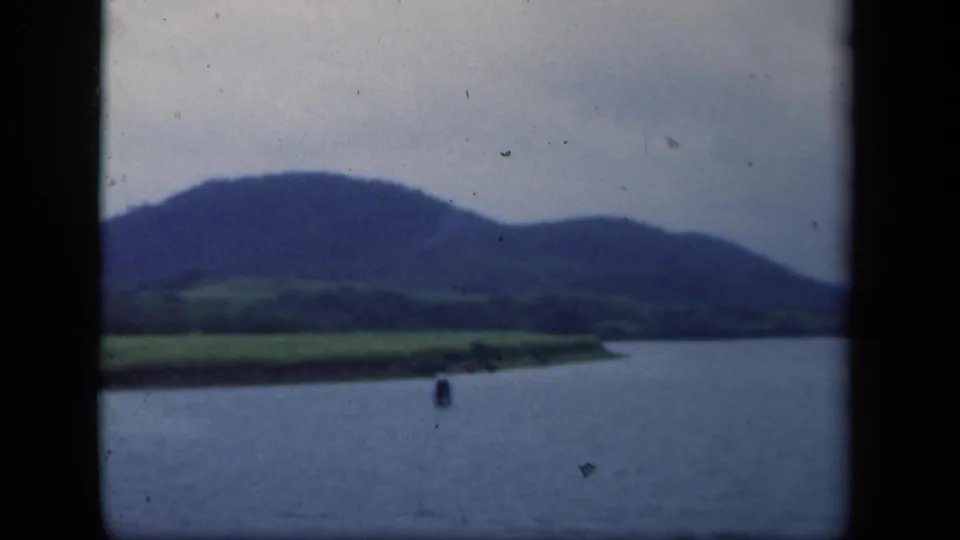 1941 New York 8mm view of water, green fields along the shore, and rounded mountain ridges beyond.