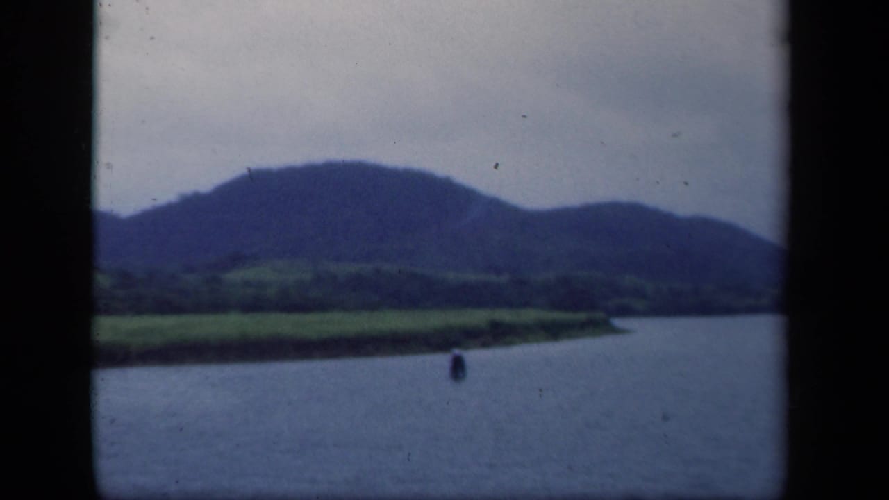 1941 New York 8mm frame showing a calm lake, green shoreline, distant mountains, and dark film gate edges.