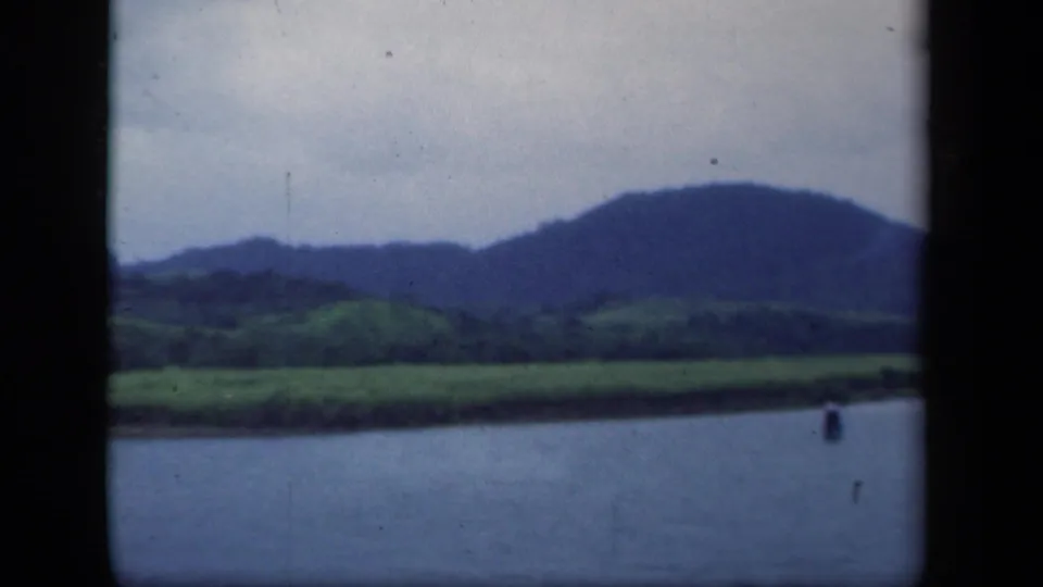 1941 New York 8mm frame looking across still lake water toward green shore and low mountains.