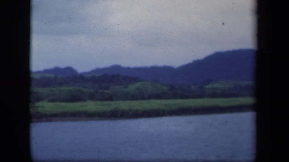 1941 New York 8mm frame showing lake foreground, green fields, and a distant mountain ridge under pale sky.