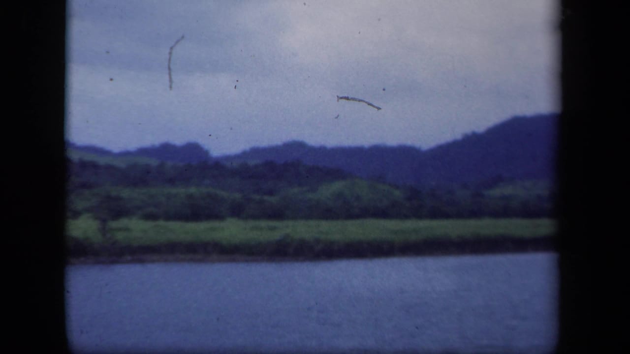 1941 8mm New York home-movie frame showing water, green marshland, dark hills, and an overcast sky.