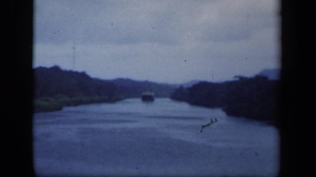 1941 8mm New York view down a broad waterway with wooded banks and a small boat in the distance.