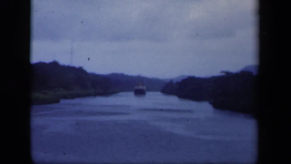 1941 8mm New York home-movie frame with a distant boat centered on a quiet marsh-lined waterway.