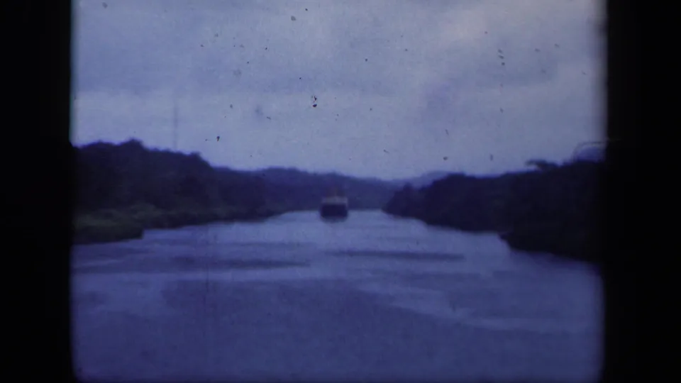 Soft 8mm frame from 1941 New York showing a vessel on a wooded waterway with visible grain and rounded frame edges.