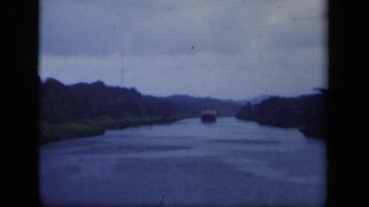 1941 8mm home-movie view of a distant vessel moving along a green New York waterway beneath a cloudy sky.