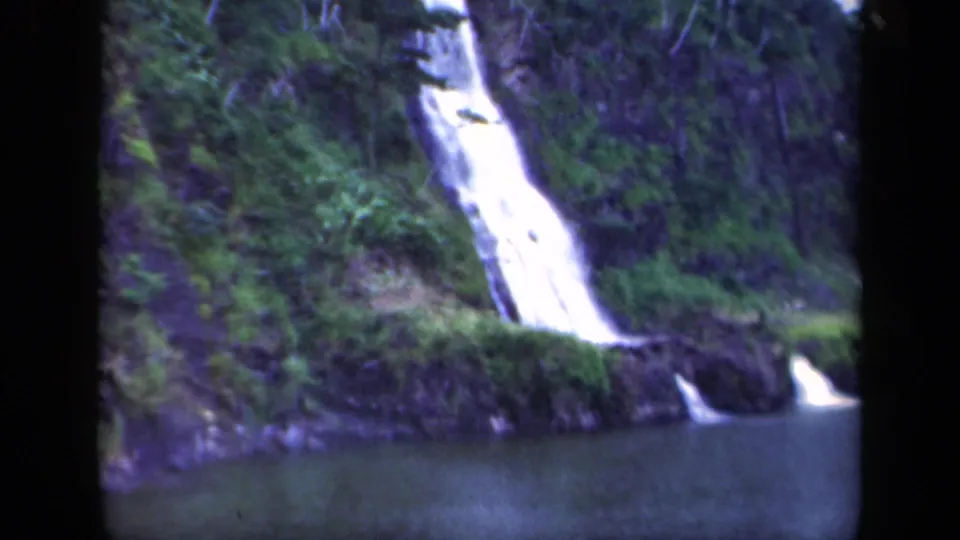 1941 8mm frame of a waterfall descending through dense greenery and rock toward a calm pool in the New York travel footage.