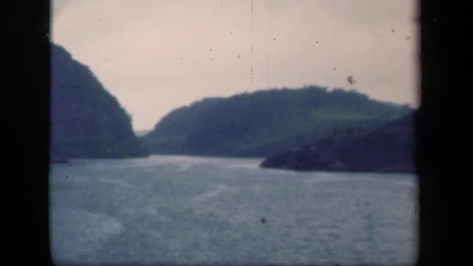 1941 8mm New York scenic frame showing calm water surrounded by wooded hills under a pale sky.