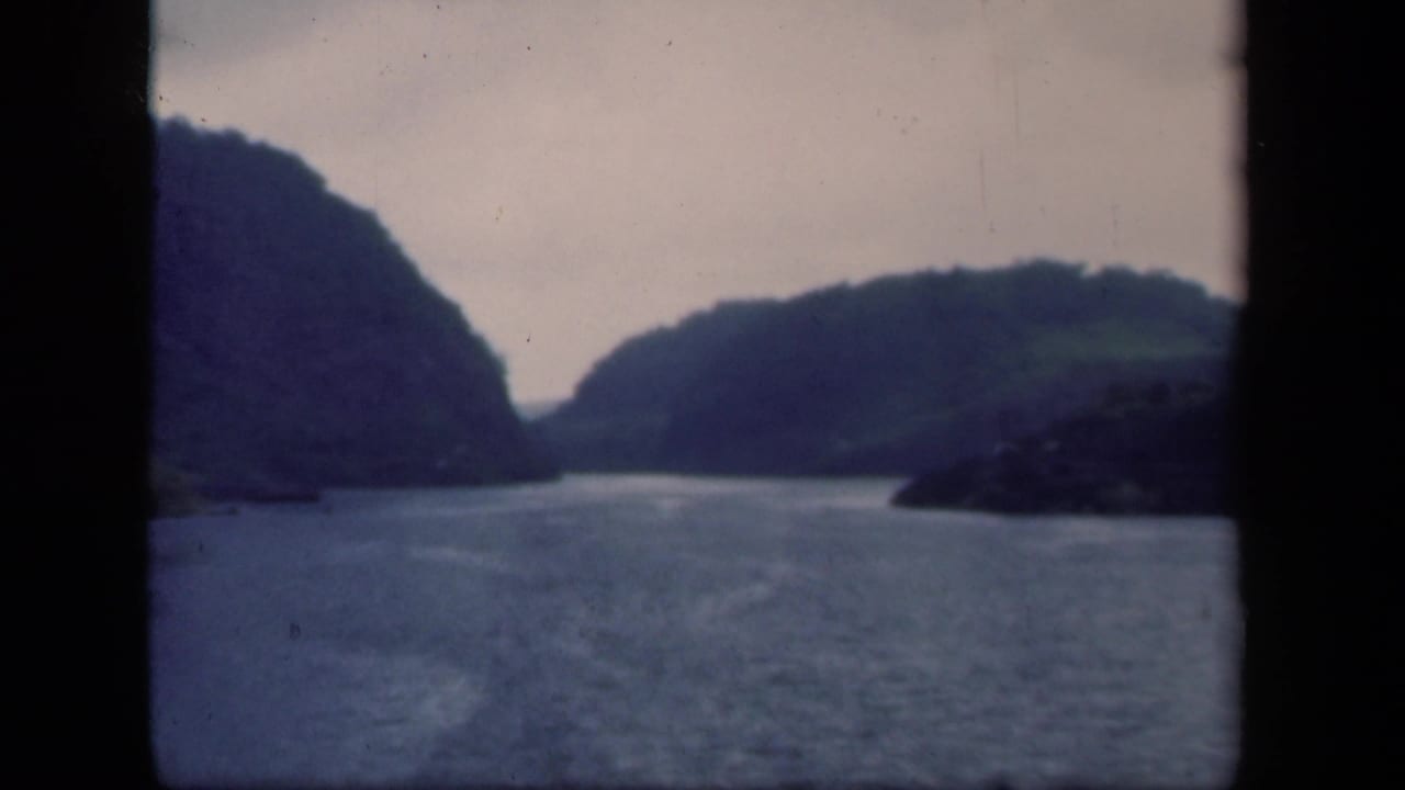 1941 New York lake view with blue-gray water, tree-covered hills, and a darker foreground shoreline area at right.