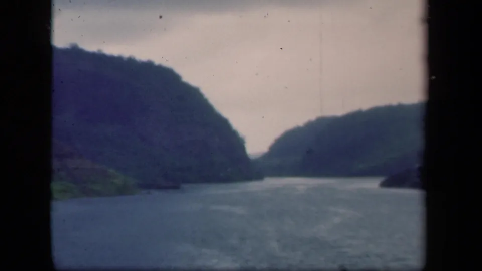 1941 New York 8mm frame of a calm waterway and layered hills, with the scene divided by a dark central edge.