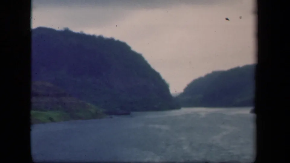 1941 New York home-movie frame showing water, green shoreline, and hills under a pale sky from a moving viewpoint.