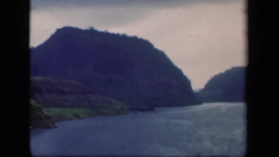 1941 New York 8mm frame of a rocky wooded hillside beside a water channel, with soft focus and visible film texture.