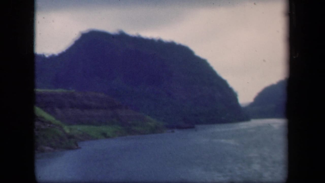 Mountain-lined waterway with green shoreline and dark 8mm frame edges.