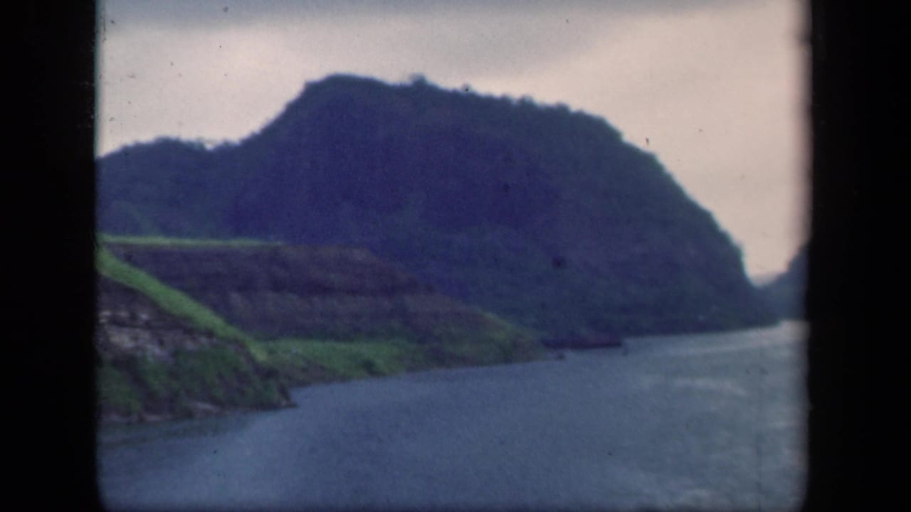 1941 New York 8mm view of water bordered by a dark forested ridge and bright green shoreline slopes.