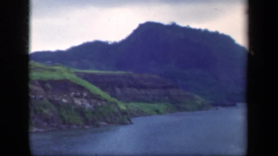 1941 New York 8mm scenic frame showing blue-gray water, green banks, and a soft-focus mountain ridge under pale cloud.