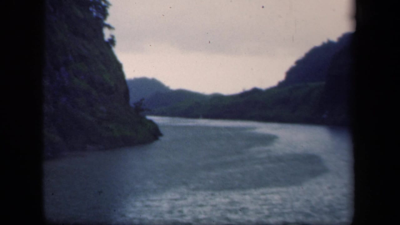 1941 New York 8mm frame showing a river winding between forested hills, seen through dark gate or camera-edge shadows.