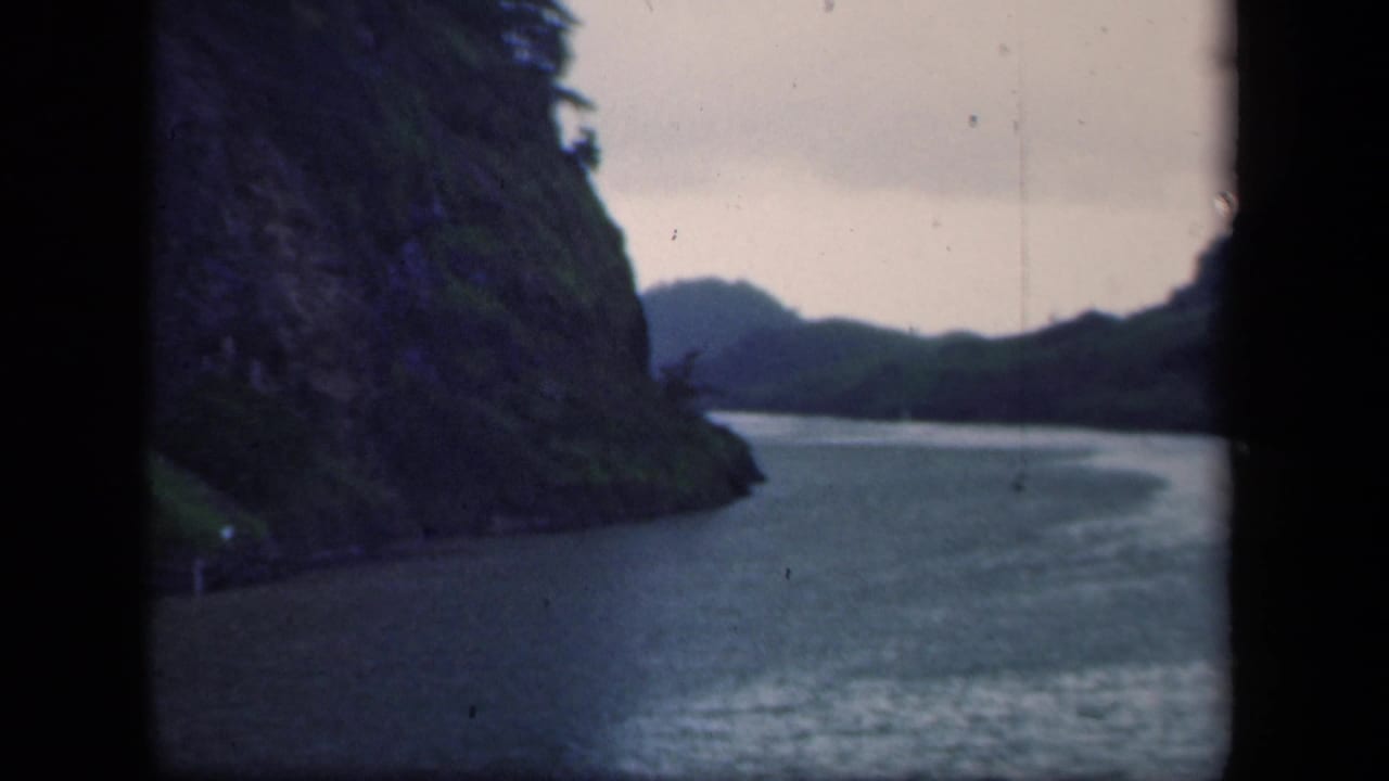 1941 New York home-movie frame of a river bend bordered by a steep wooded hillside and distant ridgeline.