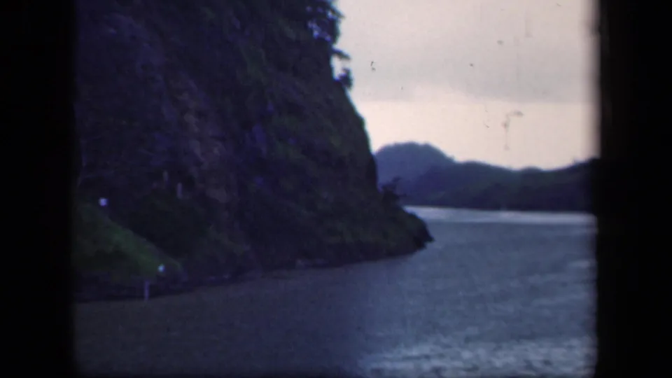 1941 New York 8mm frame with a steep forested bank dropping to a calm river, with dark frame borders visible.