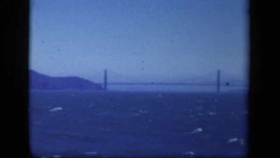 Metadata-supported 1941 New York 8mm frame showing a distant suspension bridge over water, bordered by dark film edges.