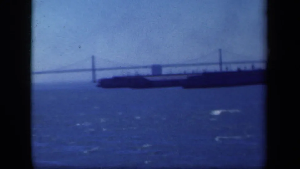 1941 New York-area 8mm frame showing the bridge tower and cables over blue water during a soft handheld panorama.