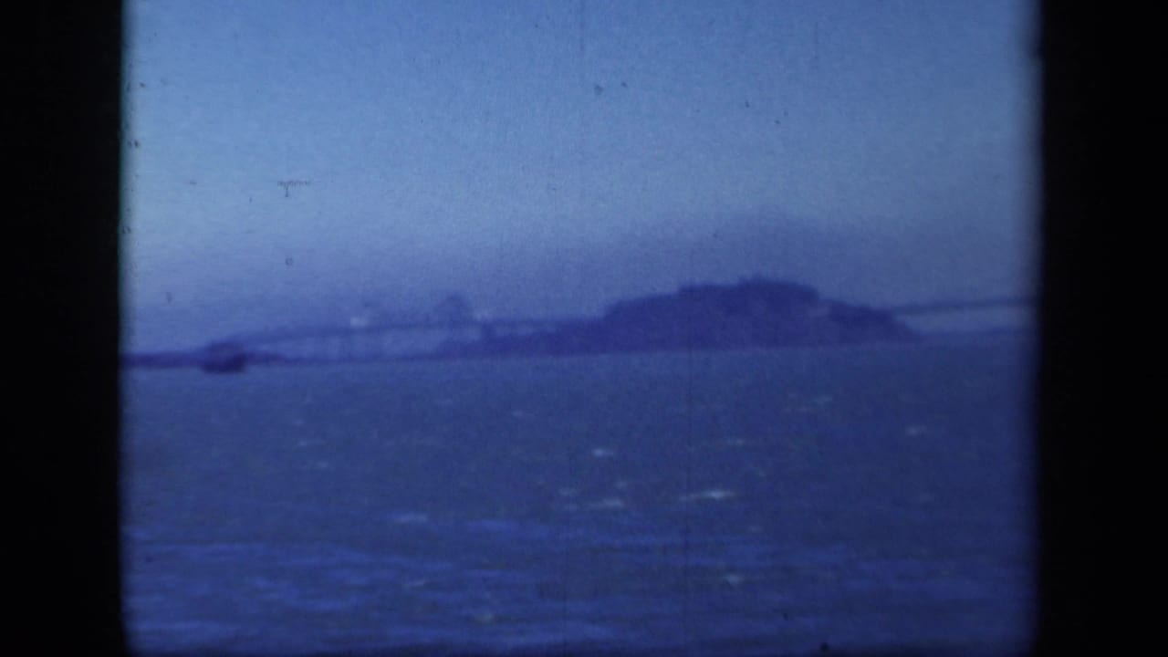 Distant island, bridge span, bay water, and dark vertical film border.