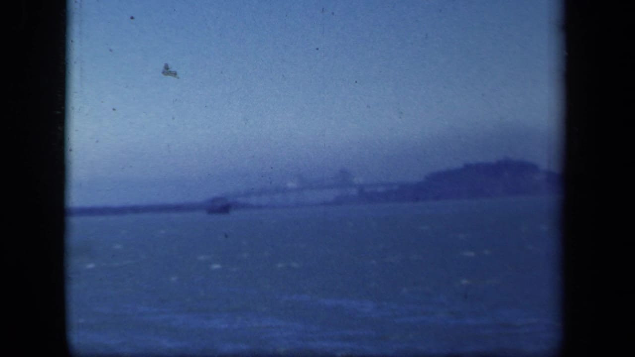Distant hazy shoreline across open water with dark film-frame borders.