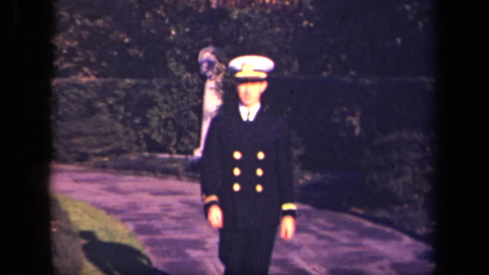 In a 1941 New York 8mm home movie, a young Navy officer walks down a garden path toward the camera.