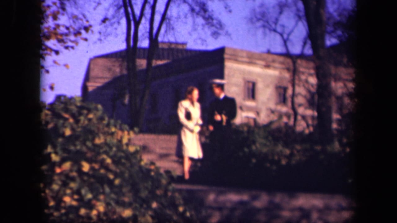 Woman in a pale dress and uniformed man walk side by side on an outdoor path.
