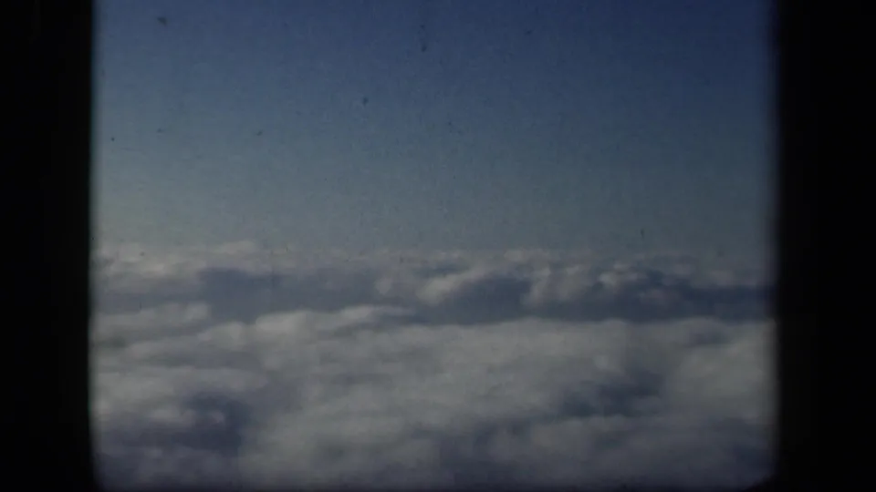 A 1941 8mm view from an airplane window, looking across clouds with a dark divider centered in the frame.