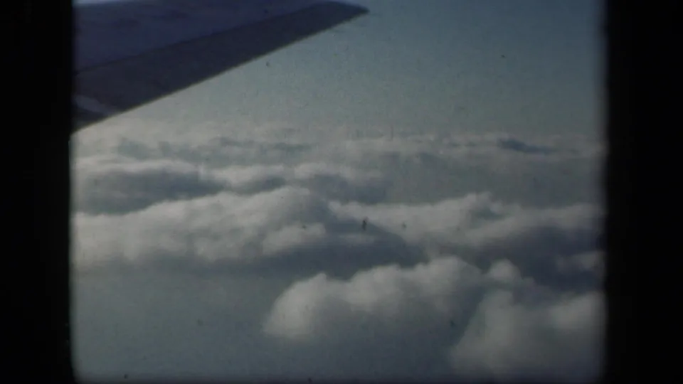 1941 8mm home-movie frame showing a cloud bank from an airplane window, with wing shadowing across the upper left.
