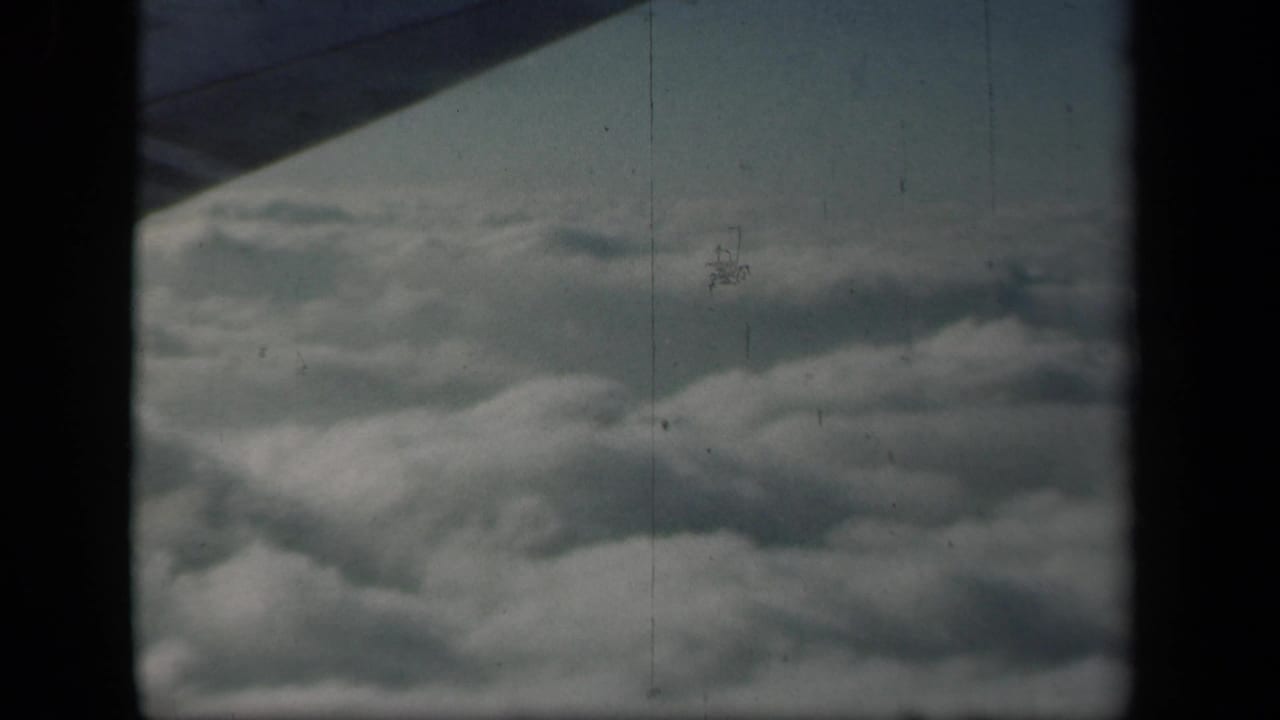 Clouds seen from an airplane window with a dark wing edge above.