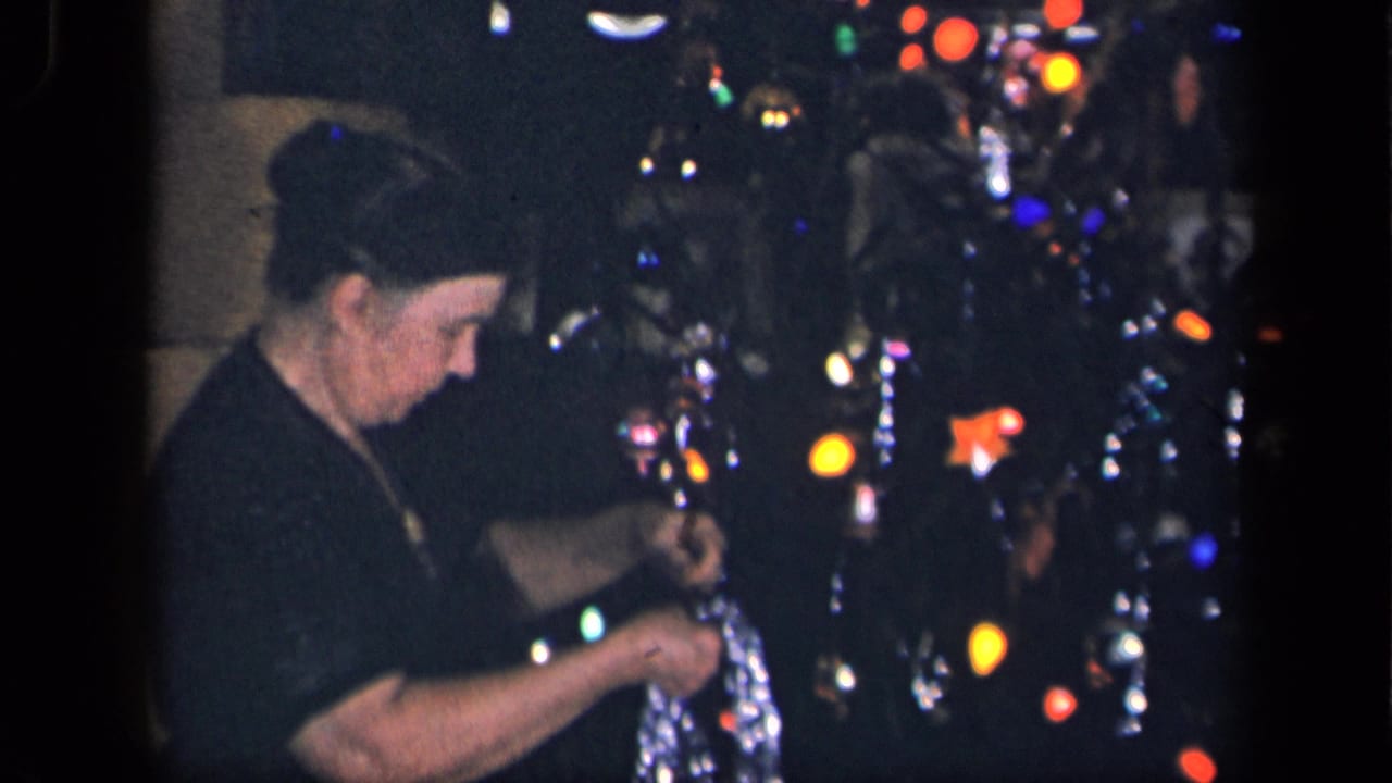 In a 1942 Sebring, Ohio home movie frame, a woman with a bun handles silver tinsel near a glowing Christmas tree.