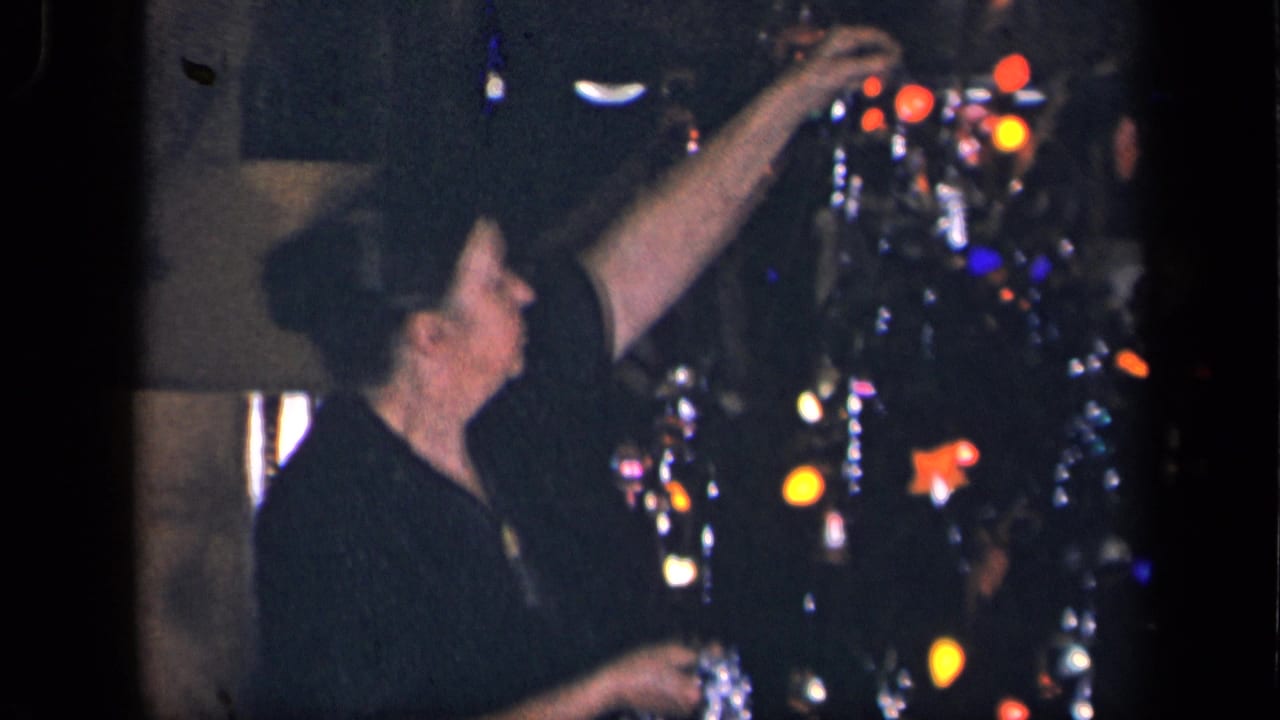 In 1942 Sebring, Ohio home-movie footage, an older woman reaches up to adjust decorations on a glowing Christmas tree.