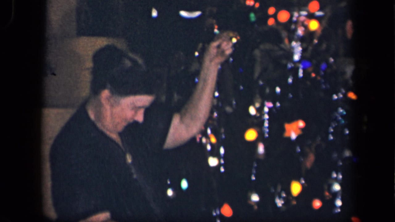 A woman in the 1942 Sebring, Ohio home-movie clip lifts her hand while working near a lit, ornamented Christmas tree.