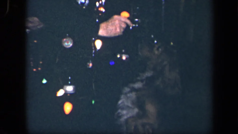 1942 Sebring, Ohio frame showing the uniformed adult holding a black dog as a small object appears near the dog's mouth amid glowing lights.