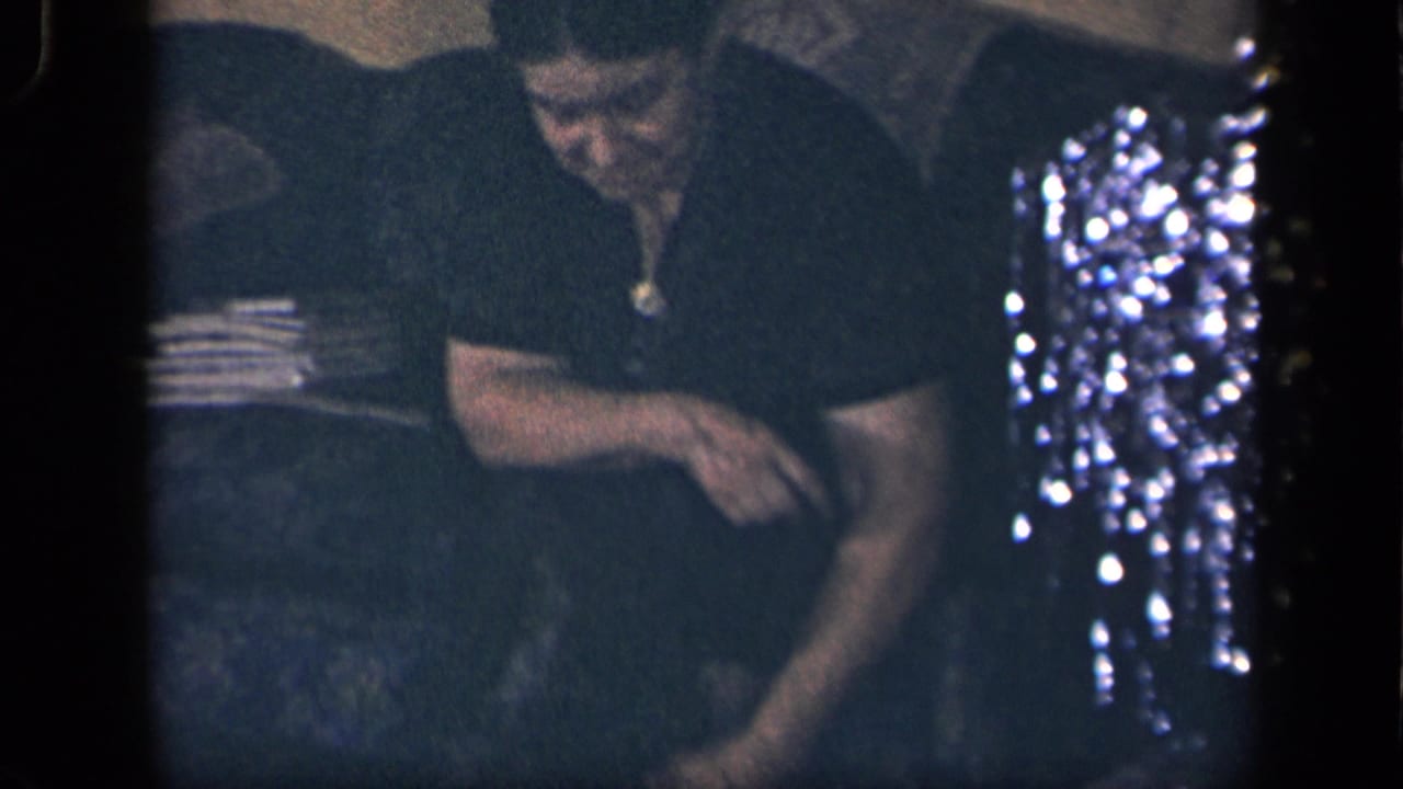 1942 Sebring, Ohio home-movie frame showing an older woman in a dark dress seated near a small dog on a couch.