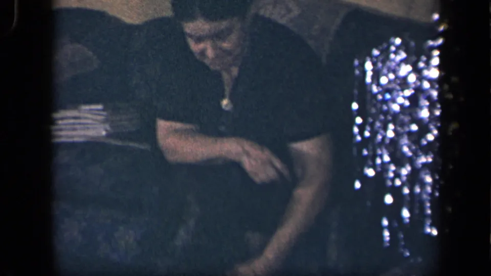 1942 Sebring, Ohio home-movie frame showing an older woman in a dark dress seated near a small dog on a couch.
