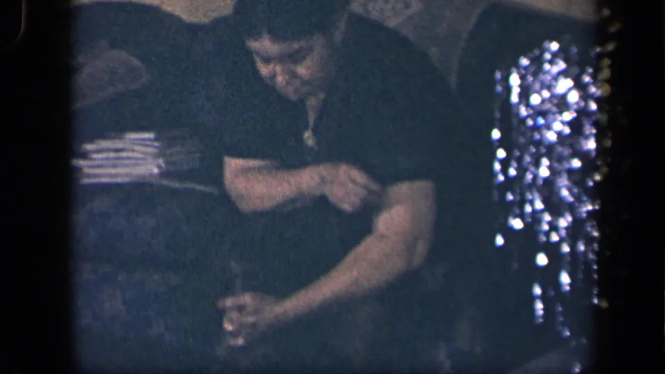1942 Sebring, Ohio home-movie frame with an older woman bent toward a small dog in a dark interior.