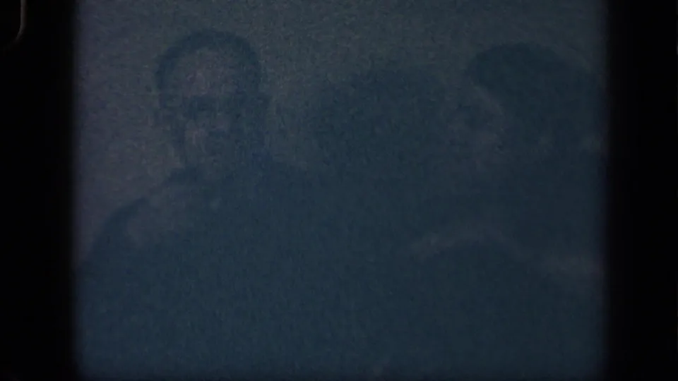 Underexposed 1942 Sebring, Ohio home-movie frame with faint figures and couch shapes barely visible.