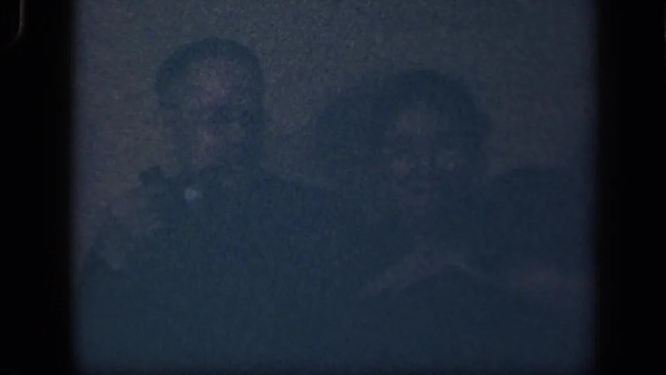 In the supplied 1942 Sebring, Ohio home-movie context, two adults appear in a dim interior, partly obscured by grain and shadow.