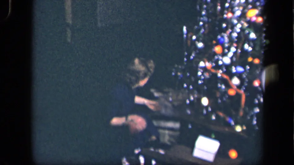 A woman sits near the decorated Christmas tree in the supplied 1942 Sebring, Ohio scene, appearing to unwrap or handle a present.