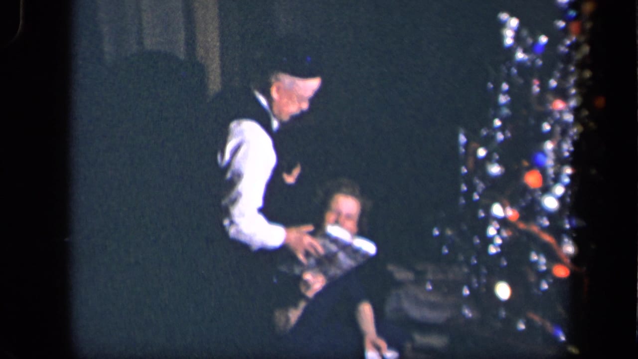 In 1942 Sebring, Ohio home-movie footage, an older man stands near a seated woman by a lighted Christmas tree.