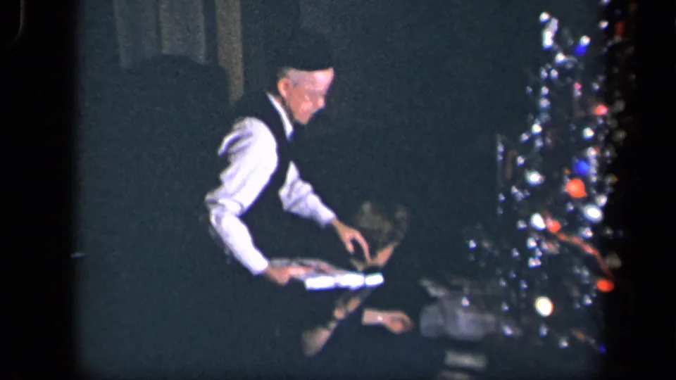 The older man leans toward the seated woman with a wrapped Christmas present in the 1942 home-movie scene.