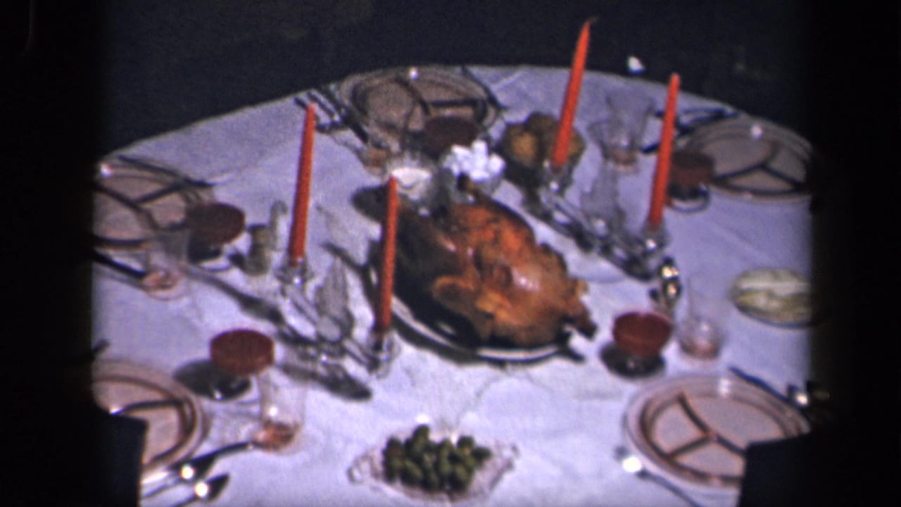 Formal dinner table with roast turkey, red candles, plates, glassware, and serving dishes.