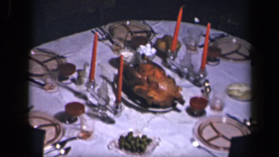 1942 Sebring, Ohio home-movie frame of a formal white-clothed dinner table centered on a roast turkey and red candles.