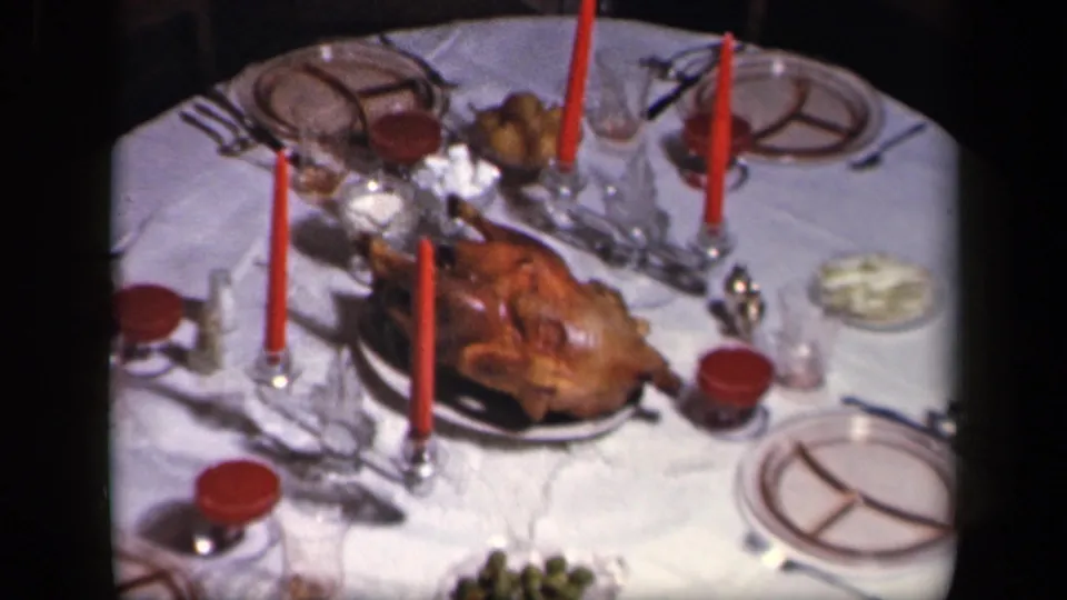Sebring, Ohio 1942 frame showing the Thanksgiving table from a slightly shifted angle, with turkey, red candles, plates and glassware visible.