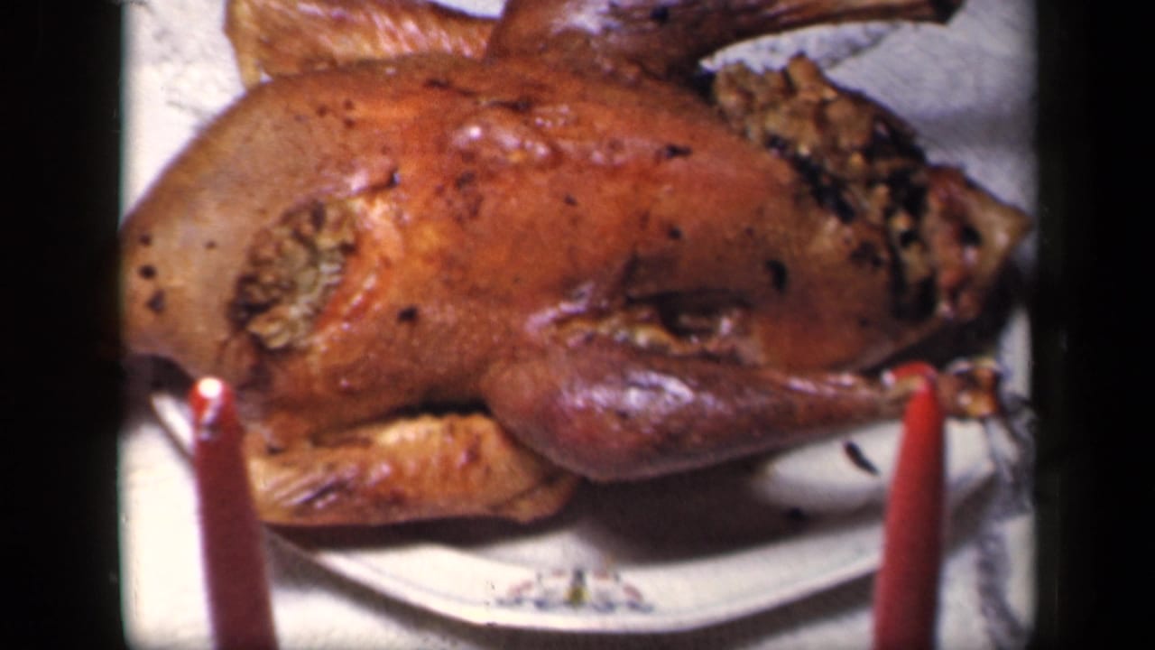 Close 1942 Sebring, Ohio view of a roasted stuffed turkey on a platter, framed by red candles on a holiday table.